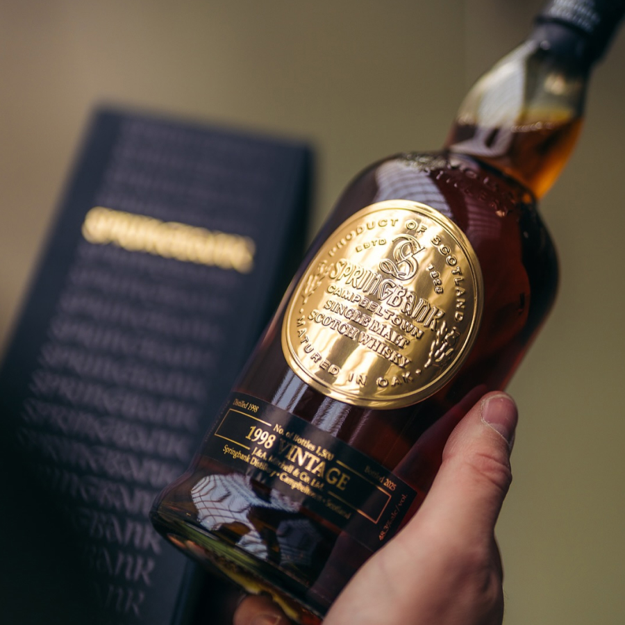 Bottle of Springbank 26yo 1998 Whisky held by a hand with a blurred box in the background