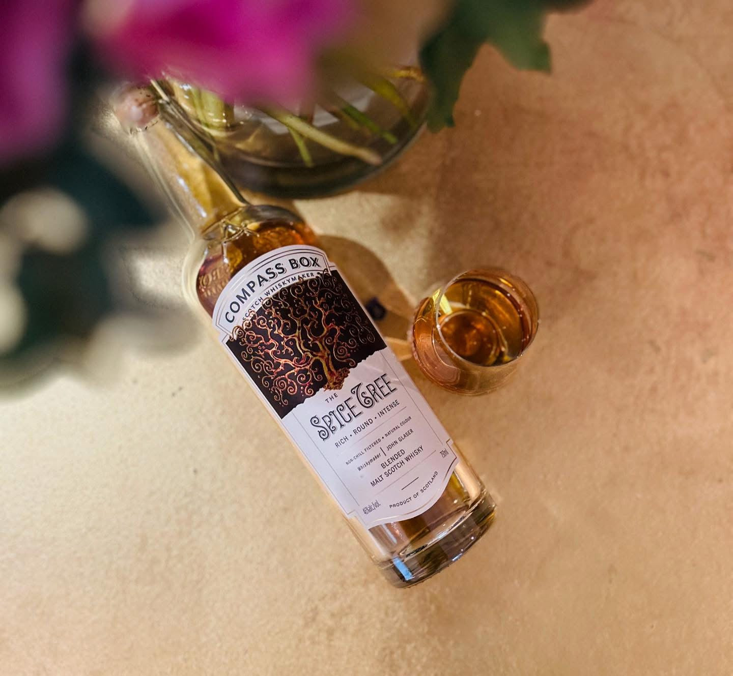 The Spice Tree Compass Box Whisky bottle in the gold background with glass of whisky 