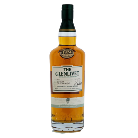 A bottle of Glenlivet 15 Pristinus Single Cask whisky with a green label and a visible signature or branding on the label.